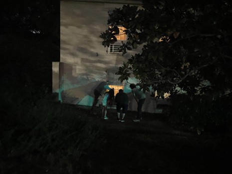 photo of a group of graduate studnets at night investigating a lighted window on a haunted history tour
