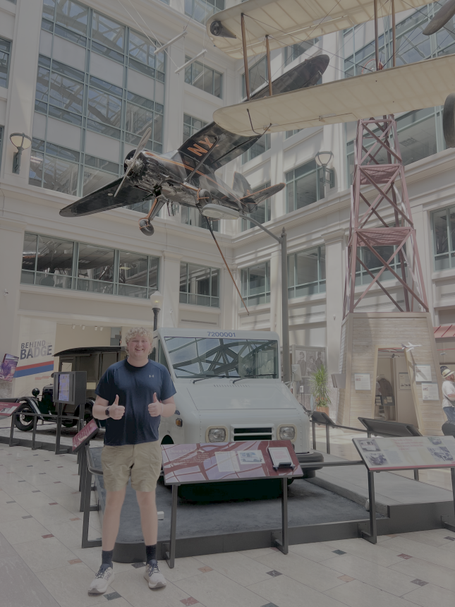 Charles Dew picture at the National Ait & Space Museum in D.C. 2025, standin in front of plane and transport exhibits