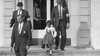 historic photo in Civil Rights history - African-American child walking down school steps, escorted by multiple U.S. Marshals
