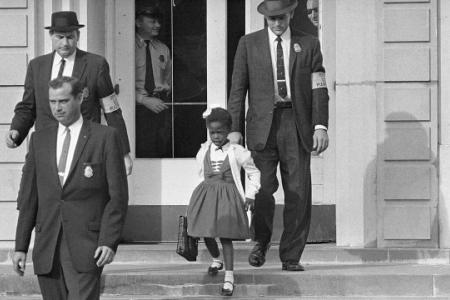 historic photo in Civil Rights history - African-American child walking down school steps, escorted by multiple U.S. Marshals