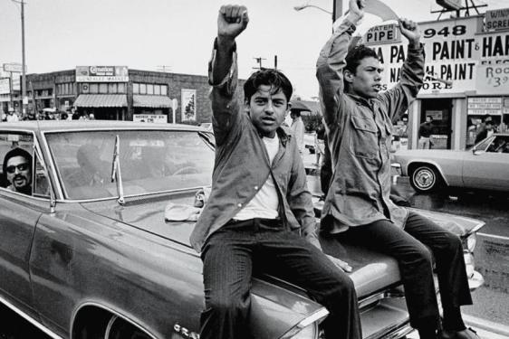 photo of men on car in parade supporting Chicano movement in U.S.